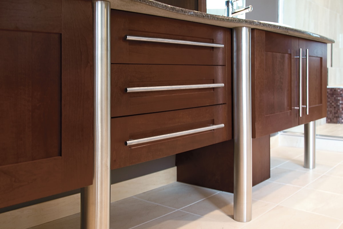 Dark brown wood vanity with stainless posts and hardware pulls.